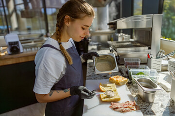An individual who is very focused prepares a delicious and delectable sandwich in a vibrant kitchen...