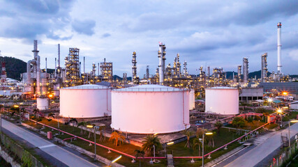 Oil refinery petrochemical plant at dusk illuminated storage tank industrial infrastructure, Oil...