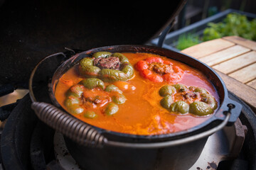 stuffed peppers with tomatoe sauce in a dutch pot, cooked on a grill, on the balcony