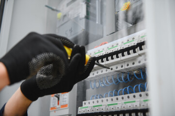 Electricians work to connect electric wires in the system, switchboard, electrical system in...