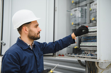 A male electrician works in a switchboard