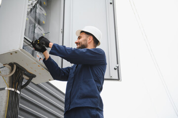 Joyful electrician mounting electric switchboard outdoors
