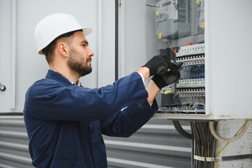 A male electrician works in a switchboard
