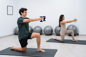 Sportsman and sportswoman doing pilates exercises with dumbbells in gym