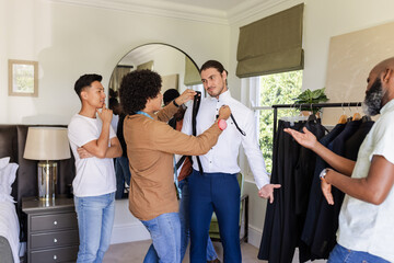 Fitting Diverse male styling team measuring client for suit in dressing room with tape measure
