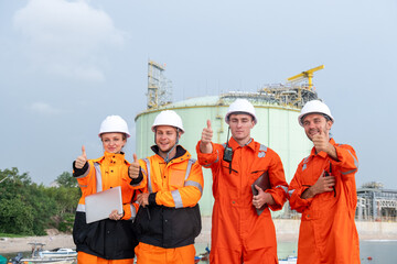 Team of workers in safety gear celebrates successful project completion at industrial site on a...