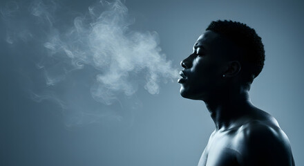 African American man exhaling smoke in a dramatic profile shot, illuminated by soft blue lighting, creating an atmospheric and contemplative mood in a minimalist setting