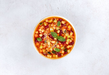 Italian minestrone soup with fresh vegetables, pasta and basil on a white background. Top view....