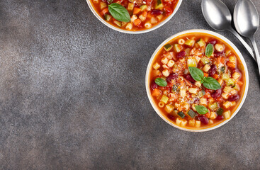 Vegetable soup with beans and pasta on gray background. Italian food. Minestrone soup. Top view. Copy space.