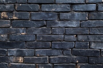 Fototapeta premium Dark gray brick wall, closely spaced rectangular blocks. Even pattern of aged bricks with slight variations in color