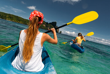 Two tanned girls kayaking in turquoise water of tropical sea. Phi-Phi islands, Krabi province, Thailand