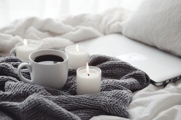 Cozy scene coffee, candles, and laptop on a knitted blanket