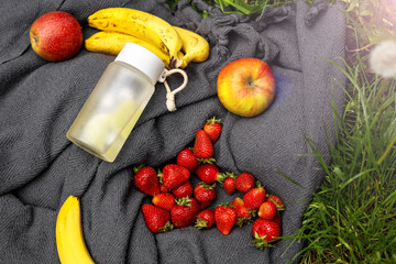 A fresh and healthy picnic spread featuring ripe bananas, apples, and strawberries alongside a...