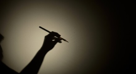 Silhouette hand holding pencil. Photo