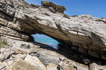 Stunning and big natural arc by the sea at the Paros Park on Paros island in Greece on a sunny day. Rocky geological landscape and natural attraction.