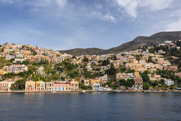 Colorful buildings on a hillside in the idyllic town of Symi by the Aegean Sea on Symi (Simi, Syme) island in Greece on a sunny day.