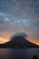 Scenic view of a cloud rolling around and over the mountain on Telendos island in Greece at sunset.