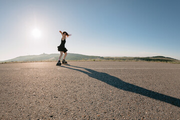 Obraz premium Woman roller skating on road, leisure activity in summer on sunny day