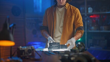 Person Inspecting Vintage Camera on Desk with Gloves
