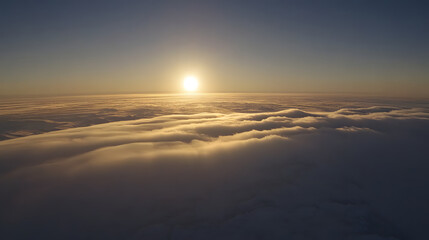 Serene aerial view of a sunset over a sea of clouds, capturing the warm glow of the sun reflecting on the horizon