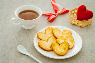 Crispy heart or butterfly puff pastry cookie and cup of tea