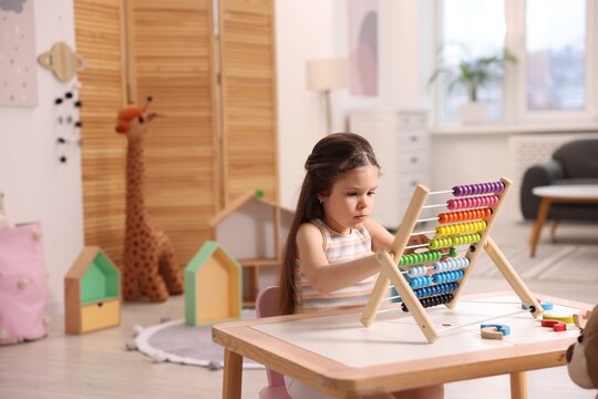 Motor skills development. Little girl playing with wooden abacus at table indoors, space for text - Powered by Adobe