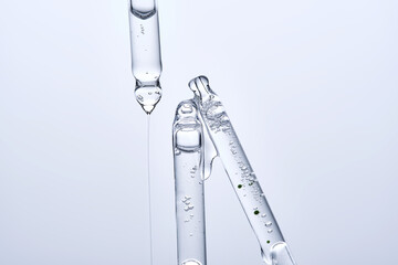 Three different face serum pipettes on a neutral background.