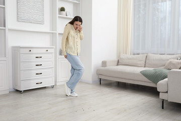 Emotional young woman looking in disgust at cockroaches on floor indoors. Pest problem