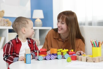 Fototapeta premium Mother and son playing with toys at table indoors
