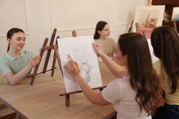 Group of women learning to draw at wooden table in class