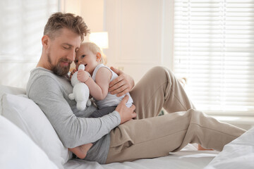 Bedtime. Happy father with his cute little baby on bed at home