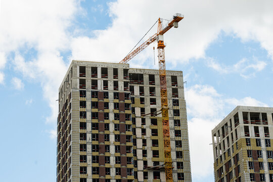 New skyscraper under construction with construction crane against cloudy sky. Highrise Building Site. - Powered by Adobe