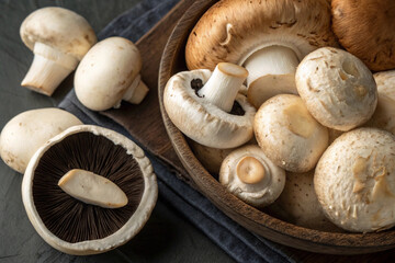 Assorted fresh mushrooms in a wooden bowl on dark rustic background