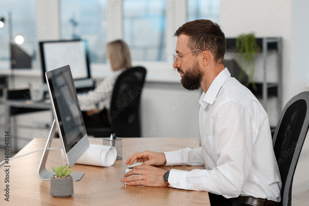 Poster technician making digital engineering drawing on computer at desk in office