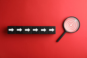 Targeting. Cubes with arrows pointing at magnifying glass with bullseye inside on red background,...