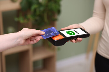 Payment terminal with NFC system. Client using credit card to pay for service indoors, closeup