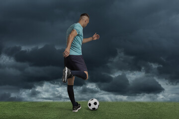 Football player kicking soccer ball under gloomy sky