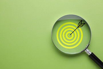 Targeting. Magnifying glass with bullseye inside on light green background, top view. Space for text