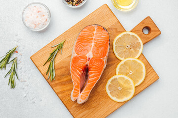 Fresh salmon fillet with lemon and herbs arranged on a wooden cutting board