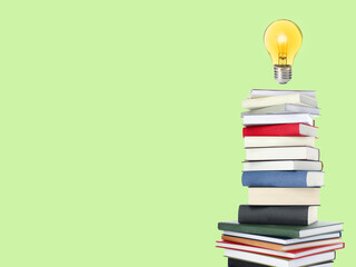 Light bulb in air over stack of books on light green background, space for text. Idea and knowledge