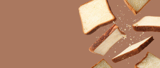Pieces of fresh toast bread and crumbs falling on brown background. Banner design with space for text