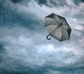 Black umbrella flying in cloudy sky under heavy rain. Stormy weather