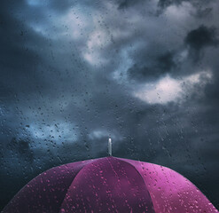 Purple umbrella under cloudy sky, view through wet window. Stormy weather