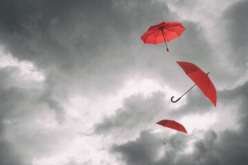 Red umbrellas flying in cloudy sky. Stormy weather