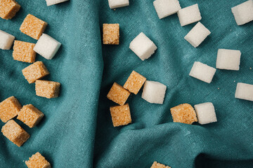 Sugar cubes scattered on a textured teal fabric background