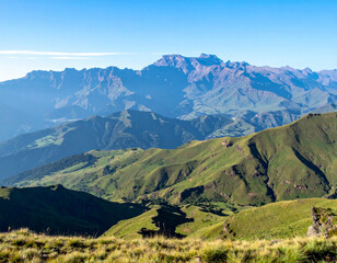 Obraz premium A serene view of the Drakensberg mountains with rolling green valleys and peaks.