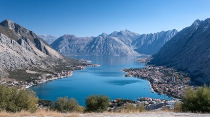 Majestic Bay View Surrounded by Mountains - Panoramic view of a stunning bay nestled between majestic mountains under a clear blue sky. Coastal town visible
