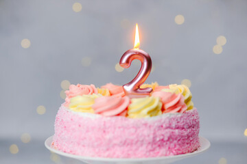 Birthday cake with a pink frosting and a candle for a two-year-old celebration