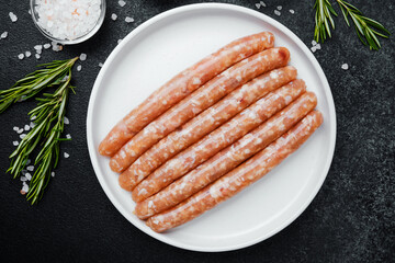 Fresh pork sausages on white plate with herbs and seasonings