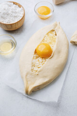 Closeup of khachapuri with egg yolk and flour on white table